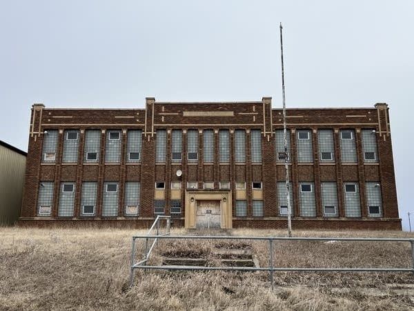Ældre centralskole i rødbrune mursten set fra den forladte skolegård